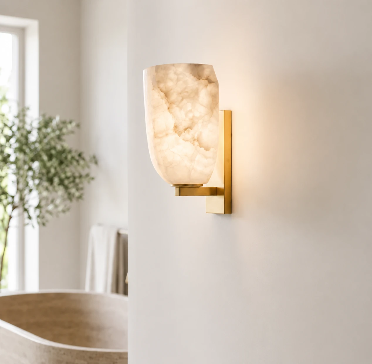 Alabaster wall light in brushed brass, lit against a pale wall