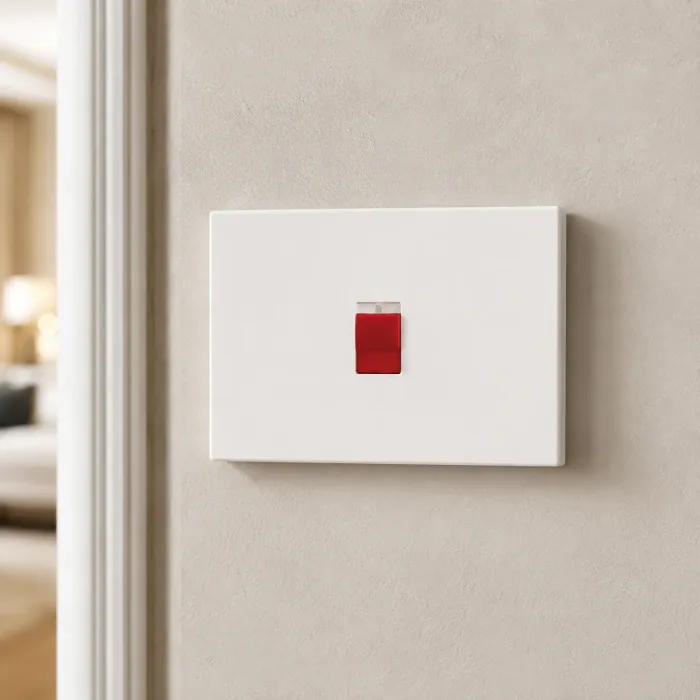 White switch with an illuminated red pilot light on a plaster wall