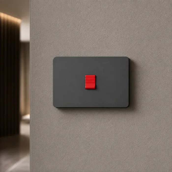 Matte black switch with a single red rocker on a grey plaster wall
