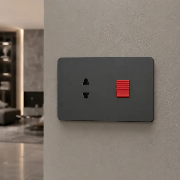Matte black plate with a two pin socket and a red rocker switch on a grey wall